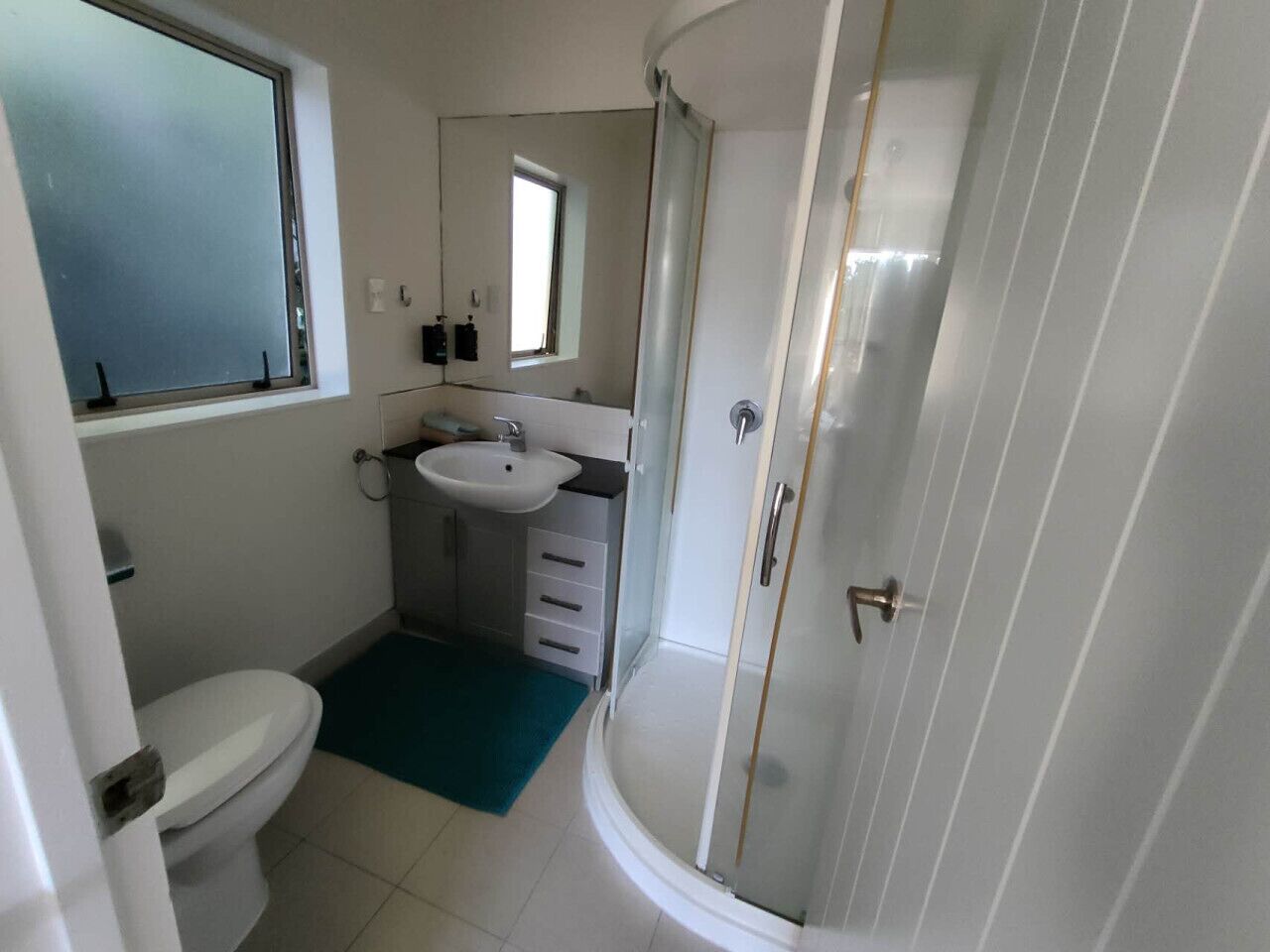Een kleine badkamer met toilet, wastafel en douche.