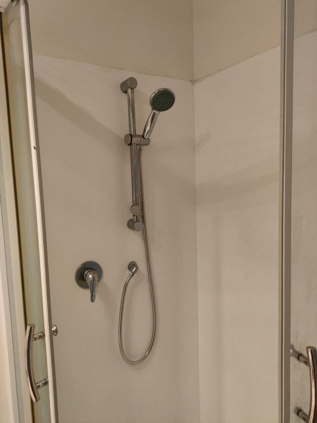 A shower with a handheld showerhead and a fixed wall-mounted showerhead.
