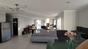 Amplia sala de estar con sofá, mesa de comedor y zona de cocina con refrigerador.