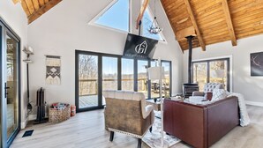 Una habitación amplia con techo alto, ventanas grandes, chimenea y un rincón de estar acogedor.