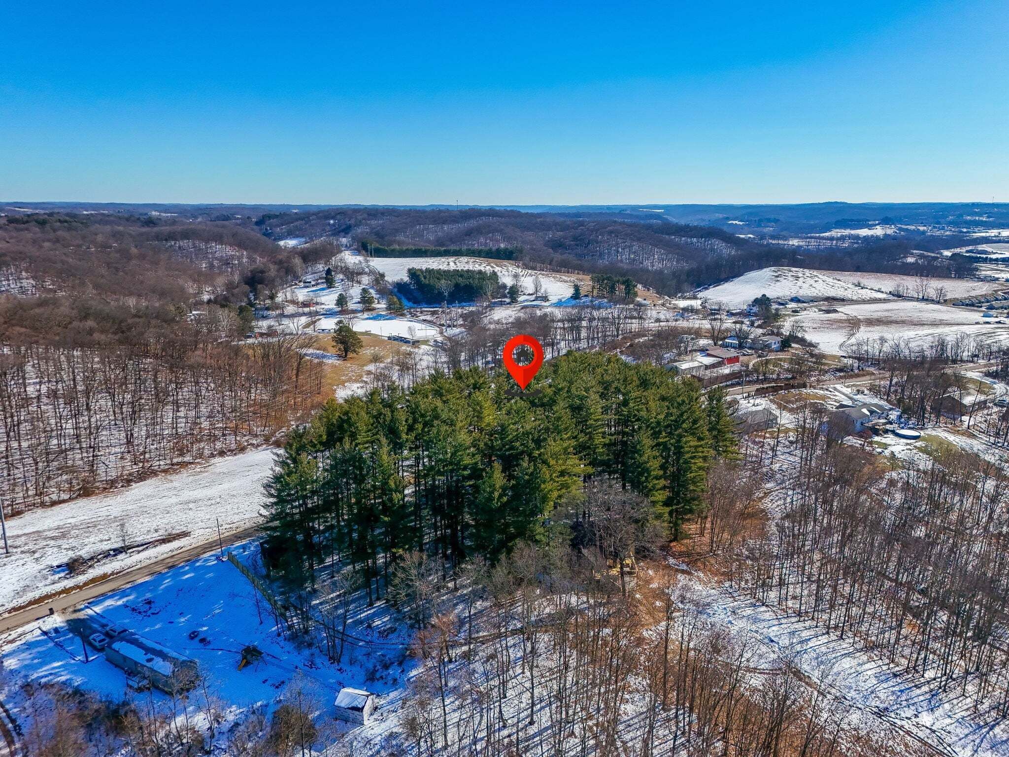 An aerial view of a snowy landscape with a red location marker.