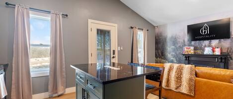 A modern kitchen with a black countertop, a dining area with a brown sofa, and a fireplace.