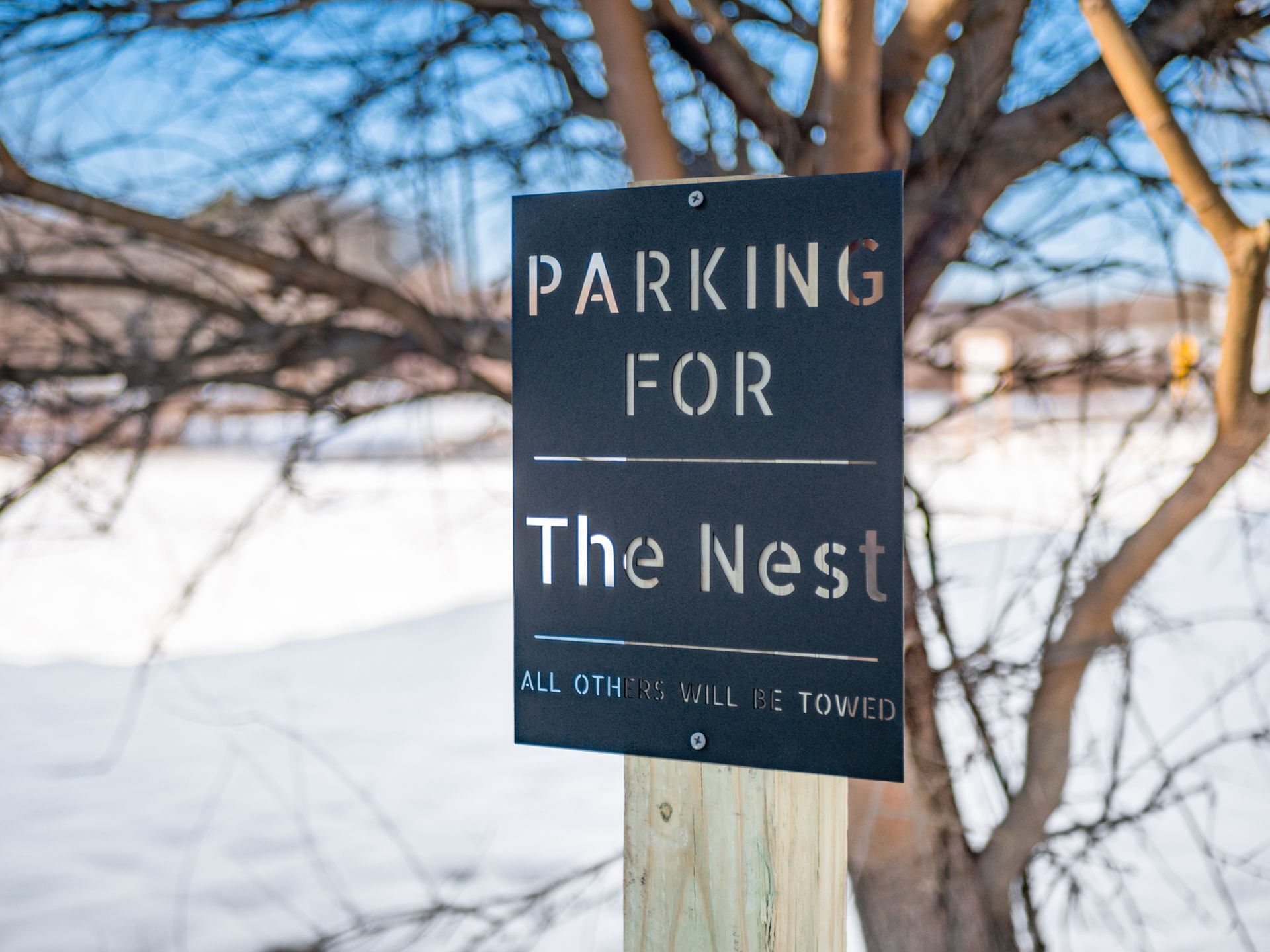 Skilt der viser "PARKING FOR The Nest" med advarsel om, at "ALLE ANDRE VIL BLIVE SLEJET VÆK".