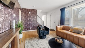 Una sala de estar moderna con un sillón azul oscuro, un sofá de cuero marrón y una mesa de centro negra.