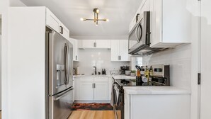 Una cocina moderna con armarios blancos, electrodomésticos de acero inoxidable y suelo de madera.