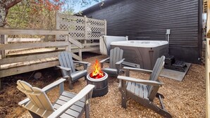 An outdoor patio with Adirondack chairs, a fire pit, and a table.