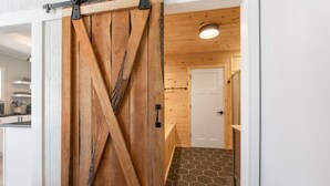 A wooden barn-style door leading to a room with a hexagonal tile floor and a white door.