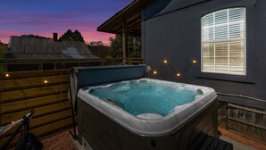 A hot tub with a wooden deck and a house in the background.