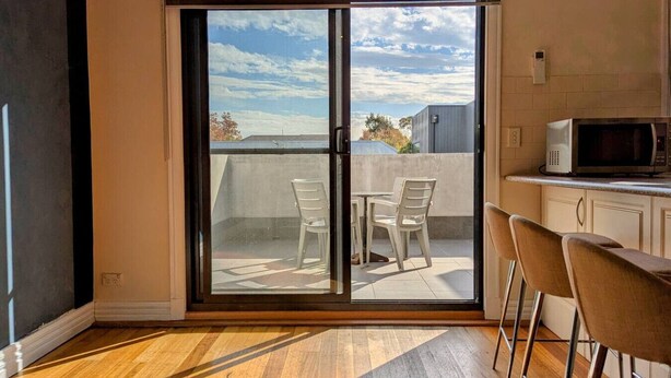 A room with a sliding glass door leading to an outdoor balcony with two chairs and a table. - Heart of Surrey Hills (Parking On Request) (Surrey Hills)
