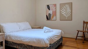 A bedroom with a bed, a chair, and two wall art pieces. - Heart of Surrey Hills (Parking On Request) (Surrey Hills)