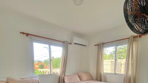 A bedroom with two beds, an air conditioning unit, a ceiling fan, and a window with curtains. - Cape Coral 1 (Cabrera)