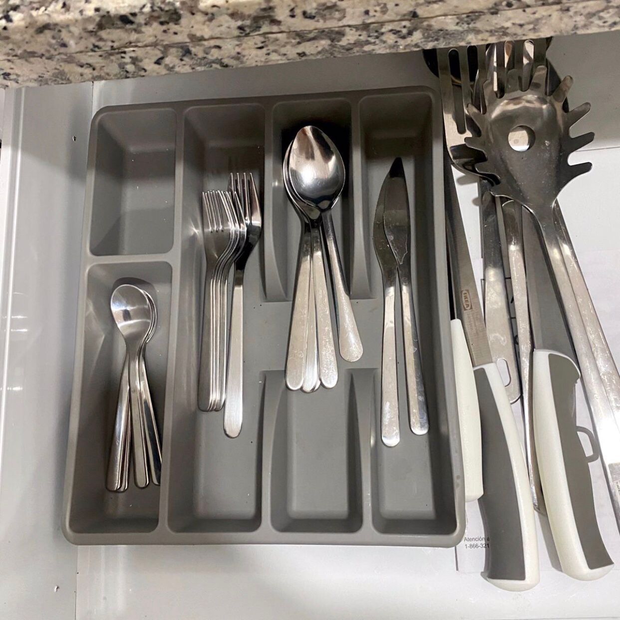 Un organizador de utensilios de cocina con compartimentos que contienen varios utensilios como tenedores, cucharas y espátulas.