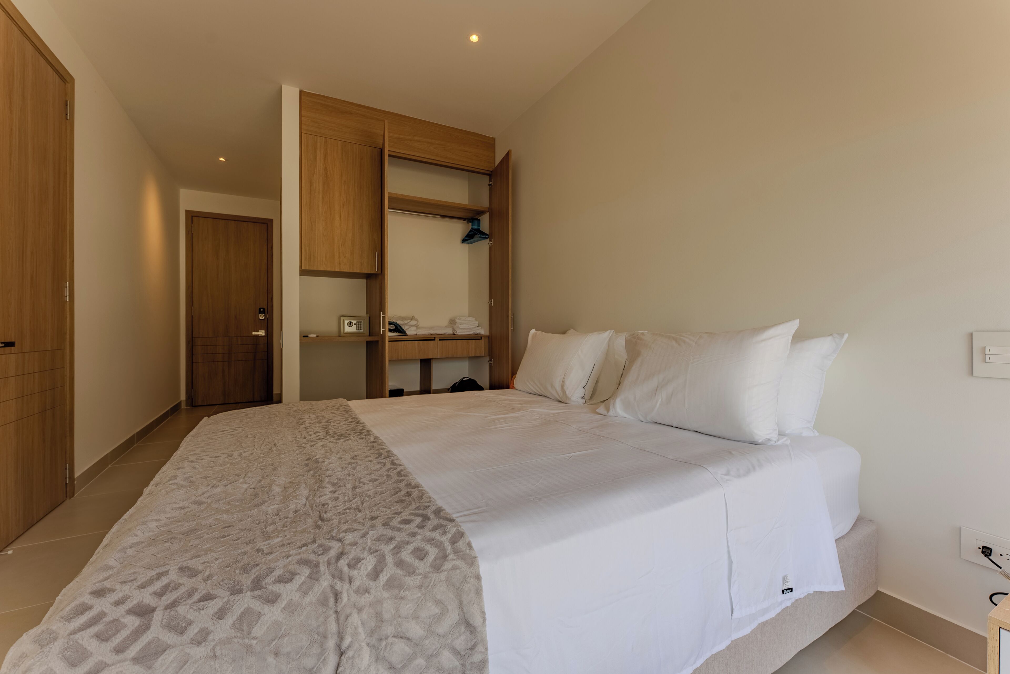 Quarto com cama, guarda-roupa, espelho e mesa de cabeceira.