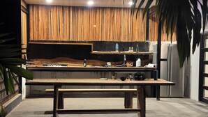 Una cocina moderna con encimera de madera, una isla central y un panel de pared de madera vertical.