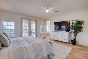 A bedroom with a bed, a ceiling fan, a TV, a dresser, and a potted plant. - Island Dream (Anna Maria)