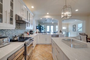 A modern kitchen with white cabinetry, a black countertop, and a hanging light fixture.