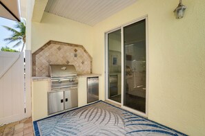 An outdoor kitchen area with a grill, a built-in oven, and a refrigerator.