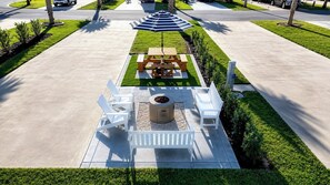 A patio area with a fire pit, seating, and a striped umbrella.