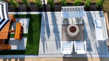 Une terrasse avec une table et des chaises en bois, un banc blanc et un jardinière circulaire ornée de baies rouges.