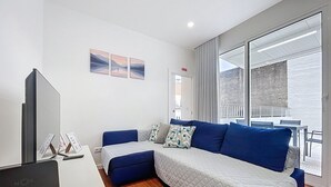 Ein modernes Zimmer mit einer Couch, einem Fernseher und einem Balkon mit Blick.