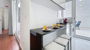 Eine moderne Küche mit dunkler Arbeitsplatte, weißen Schränken und einem Fenster mit Blick auf eine verschneite Landschaft.