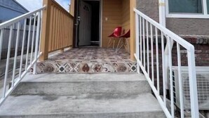 Una casa con porche cubierto, una silla roja y el número 7199 en la puerta.