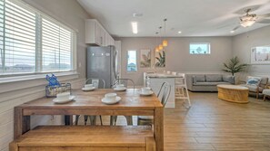 A modern kitchen with a dining table set for four, a refrigerator, and a built-in oven. - Sleeps 33! 4 Condos, Walk to the Beach, Resort-style Pool, Endless Summer Resort (Port Aransas)