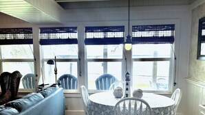 A dining area with a round table, white chairs, and a blue patterned tablecloth. - Lakeside Cabin With Your Own Personal Beach and Expansive Lake View (Point Blank)