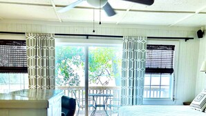 A bedroom with a bed, a wooden desk, a ceiling fan, and a view of the outdoors through a sliding glass door. - Lakeside Cabin With Your Own Personal Beach and Expansive Lake View (Point Blank)