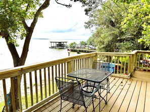 A wooden deck with a table and chairs overlooking a lake, a dock, and a boat. - Lakeside Cabin With Your Own Personal Beach and Expansive Lake View (Point Blank)