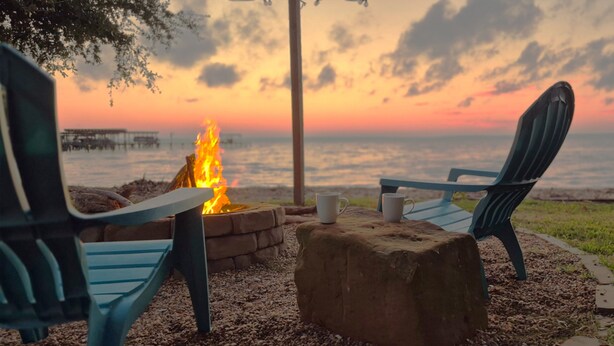 Two chairs facing a fire pit with a view of the ocean and a sunset. - Lakeside Cabin With Your Own Personal Beach and Expansive Lake View (Point Blank)