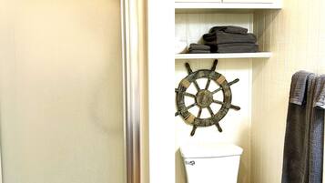 Une salle de bain équipée d’une douche, de toilettes et décorée avec un volant de navire.