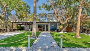 A modern house with a covered patio, a lawn, and a gravel pathway. - Charming spacious 3-bedroom house walking minutes from Siesta Key Beach (Siesta Key)