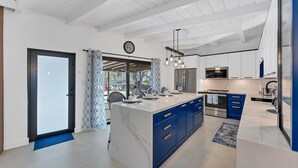 A modern kitchen with a large island, blue cabinets, and a hanging light fixture. - Charming spacious 3-bedroom house walking minutes from Siesta Key Beach (Siesta Key)