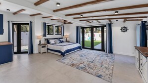 A bedroom with a bed, bedside tables, a ceiling fan, and a view to the outside. - Charming spacious 3-bedroom house walking minutes from Siesta Key Beach (Siesta Key)