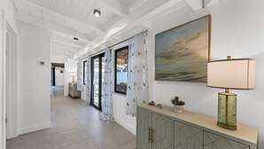 A hallway with a geometric-patterned cabinet, a landscape painting, and a lamp. - Charming spacious 3-bedroom house walking minutes from Siesta Key Beach (Siesta Key)