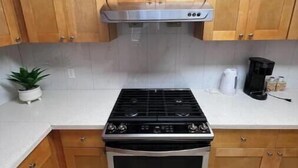 A kitchen with wooden cabinets, a stainless steel stove, and a coffee maker on the countertop.