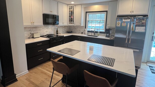 A modern kitchen with white cabinets, a large island with bar stools, a built-in microwave, and a refrigerator. - 3 Bedroom Ranch with private inground pool just 12 mi. from SPAC and racetrack (Burnt Hills)