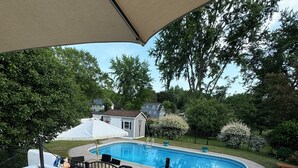 A backyard with a swimming pool, a covered patio area, and a deck with a table and chairs. - 3 Bedroom Ranch with private inground pool just 12 mi. from SPAC and racetrack (Burnt Hills)