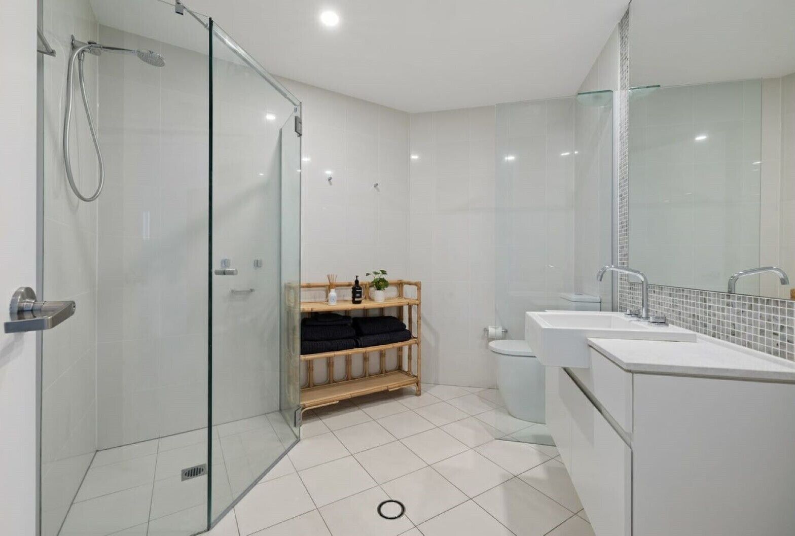 Une salle de bain moderne avec une douche à parois de verre, des toilettes et un meuble-lavabo avec un miroir.