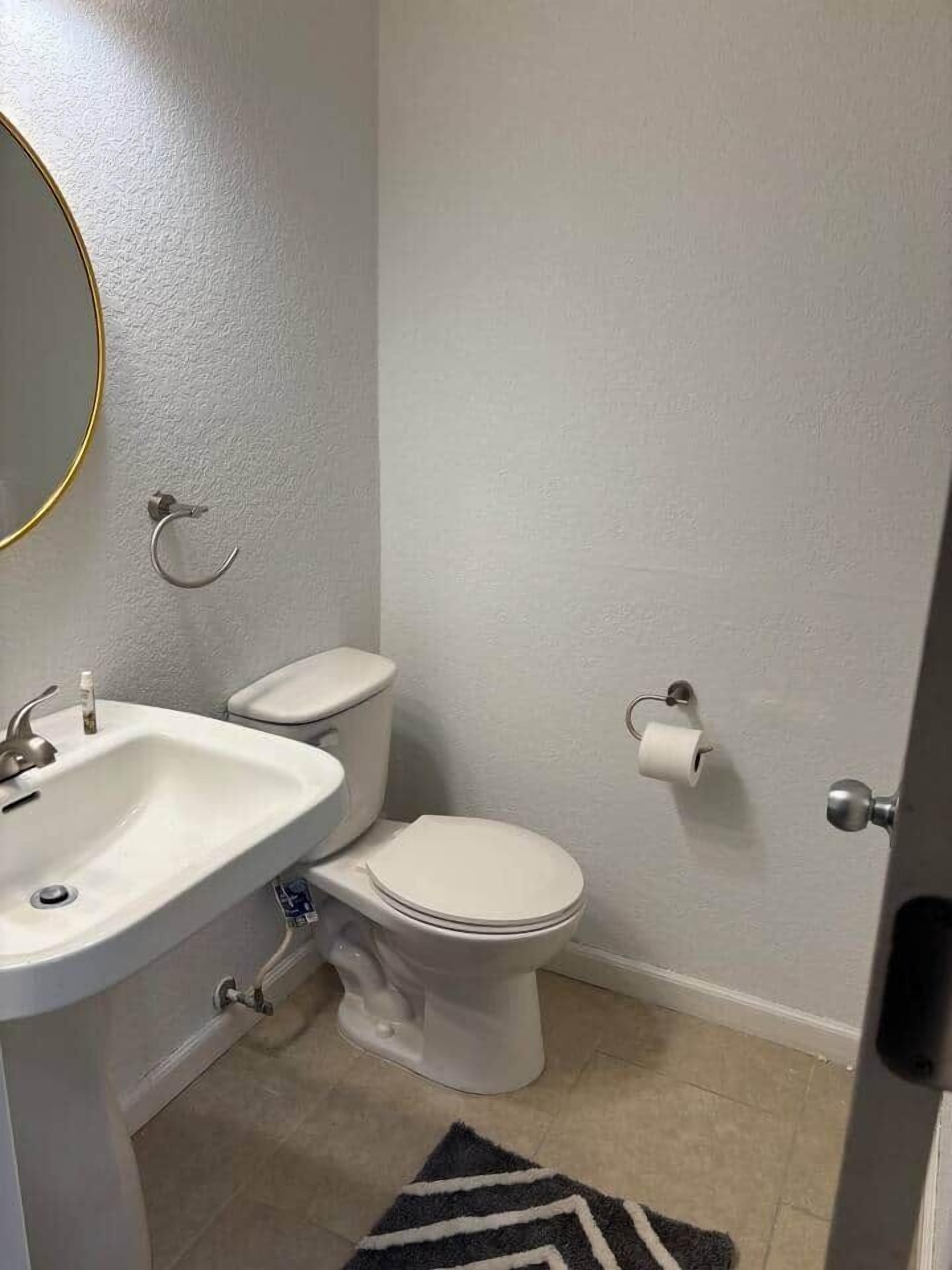 A bathroom with a white sink, toilet, and a towel rack.