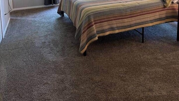 A bedroom with a bed, curtains, a window, and a wall-mounted light fixture. - Cedarwood Chateau (Cambridge)