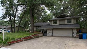 A two-story house with a garage, surrounded by trees and a well-maintained lawn. - Cedarwood Chateau (Cambridge)