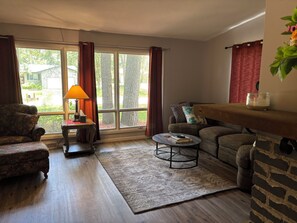 A living room with a sofa, armchair, coffee table, and a lamp.