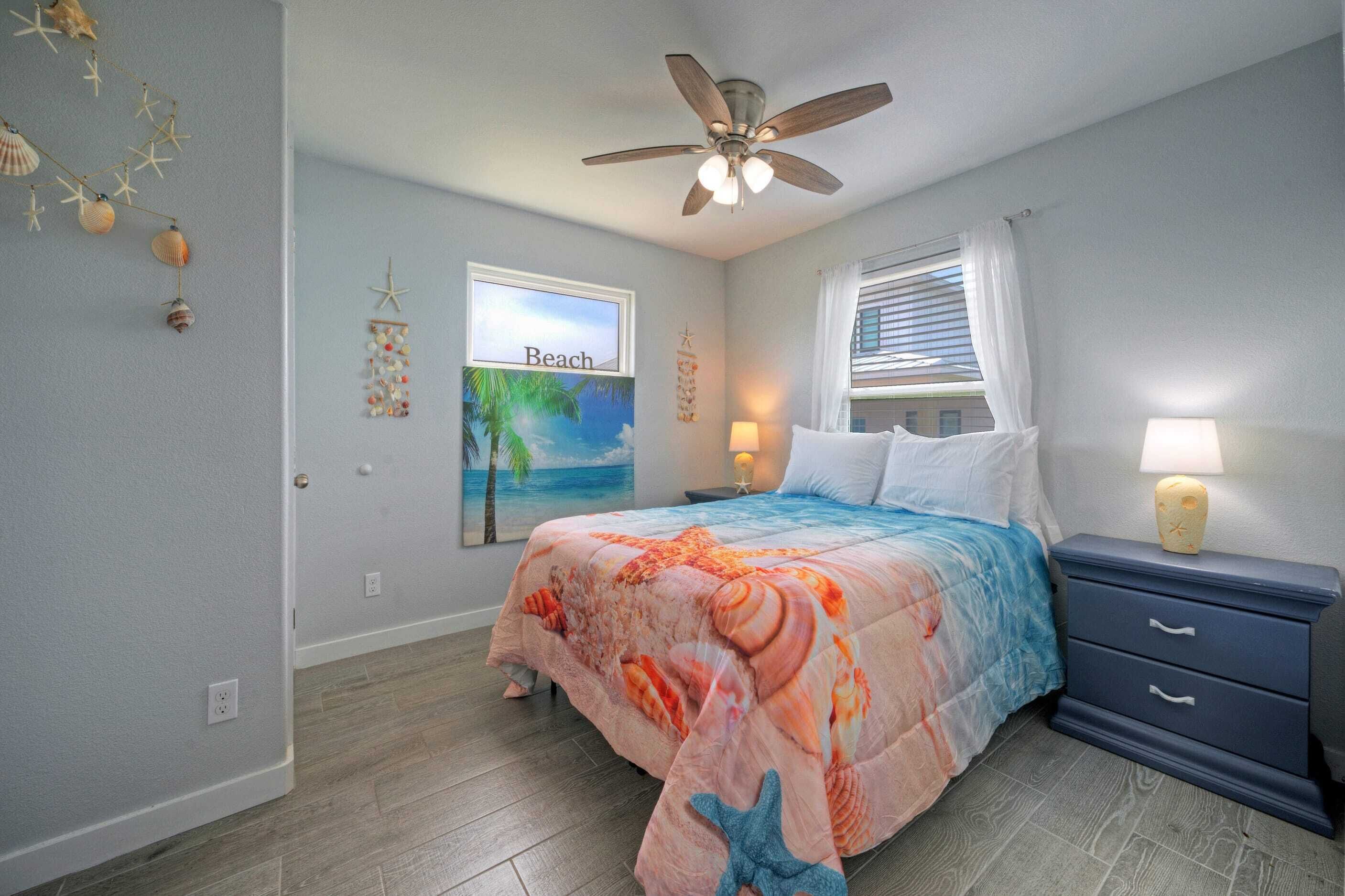 A bedroom with a bed, a ceiling fan, a nightstand, and a window with blinds.