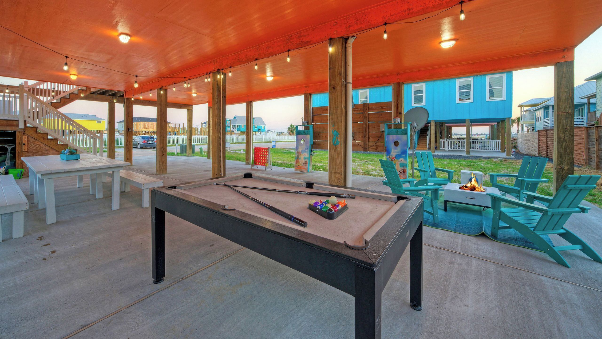 An outdoor pool table with surrounding seating and a covered area.