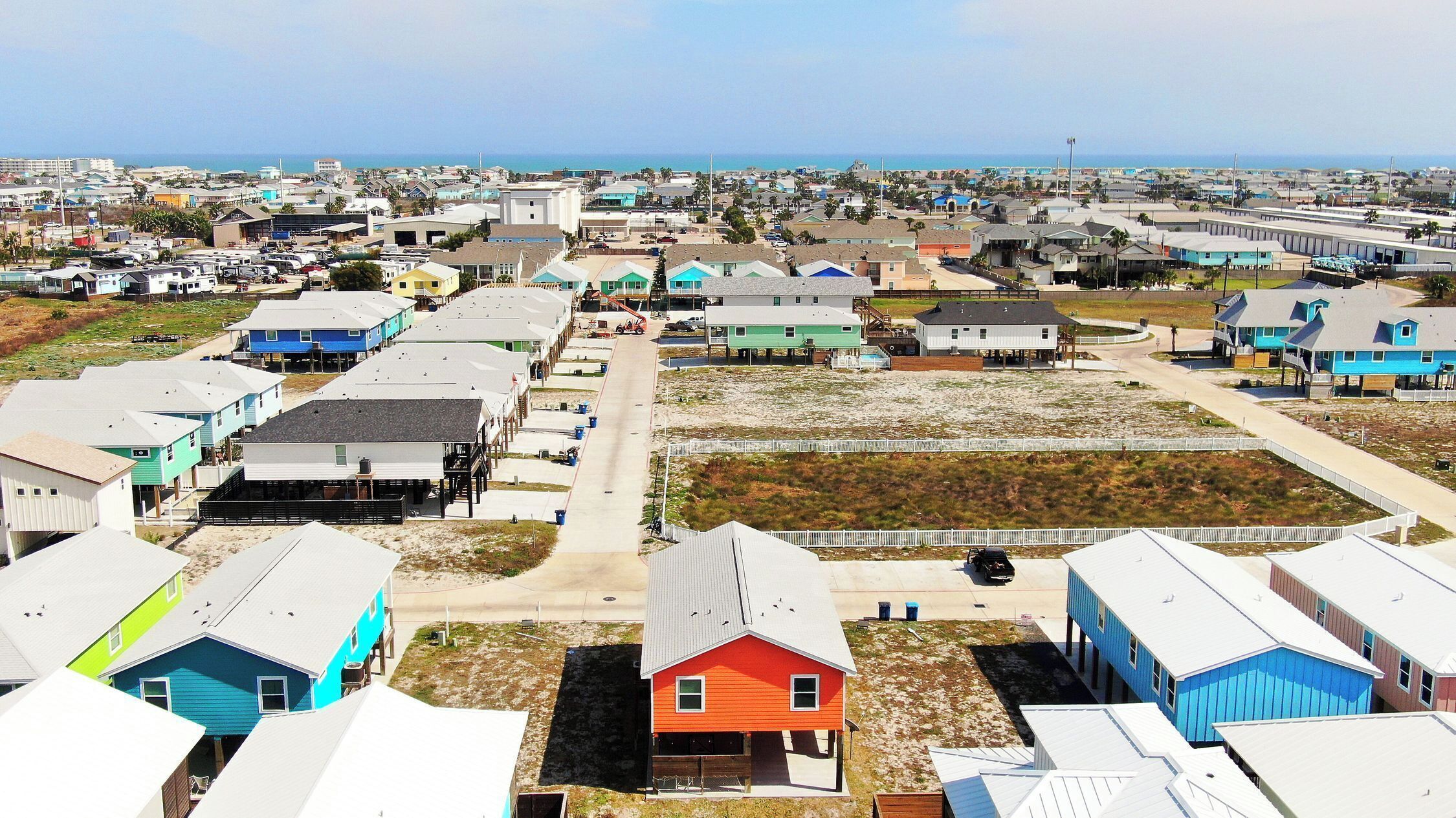 A residential area with houses, a beach, and a clear sky.