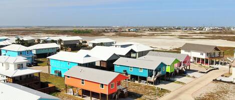 Una zona residencial costera con casas coloridas, una playa arenosa y un cielo despejado.