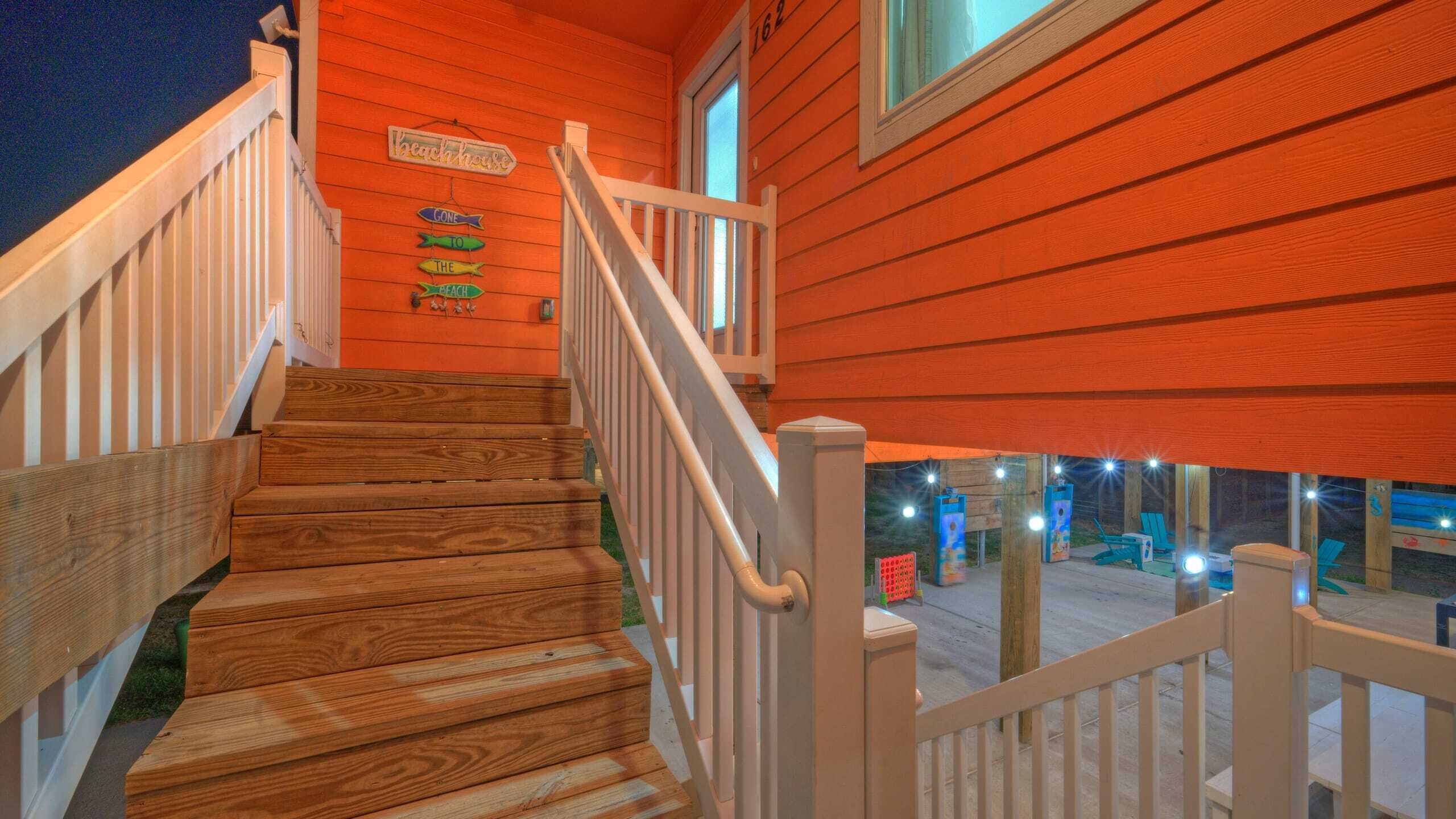 A wooden staircase leading to a porch with a sign reading "Beachhouse."