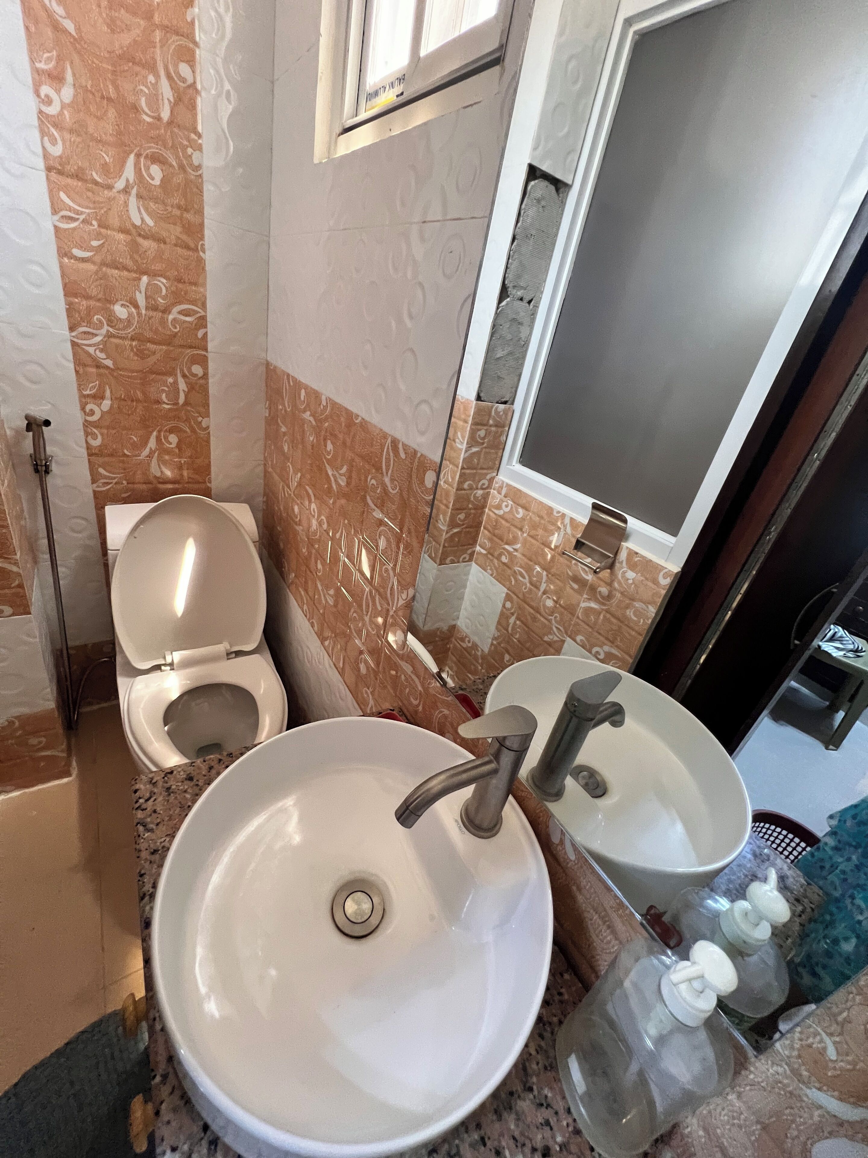 A bathroom with a toilet, two sinks, and a mirror.